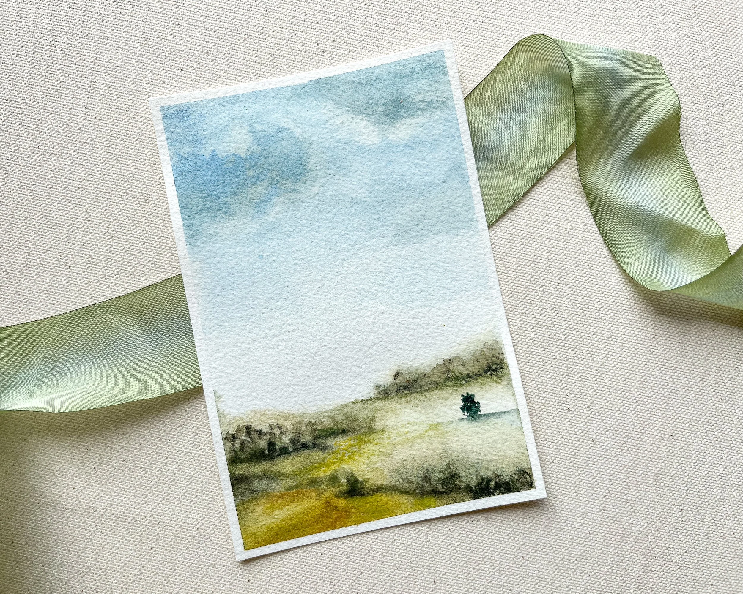 Green rolling hills in watercolor under blue sky - a watercolor painting