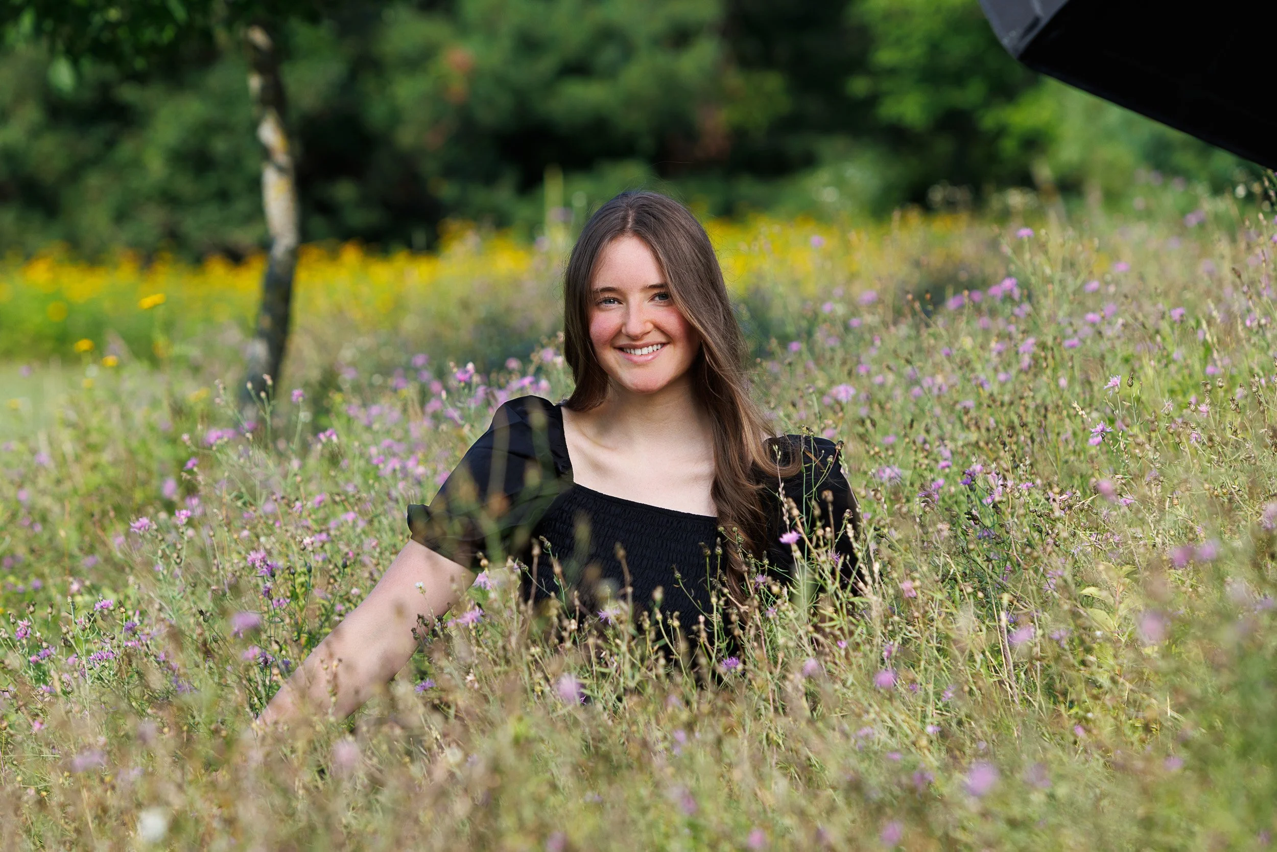 Girls senior pictures in a flower field with a black dress, Rice Lake, WI.