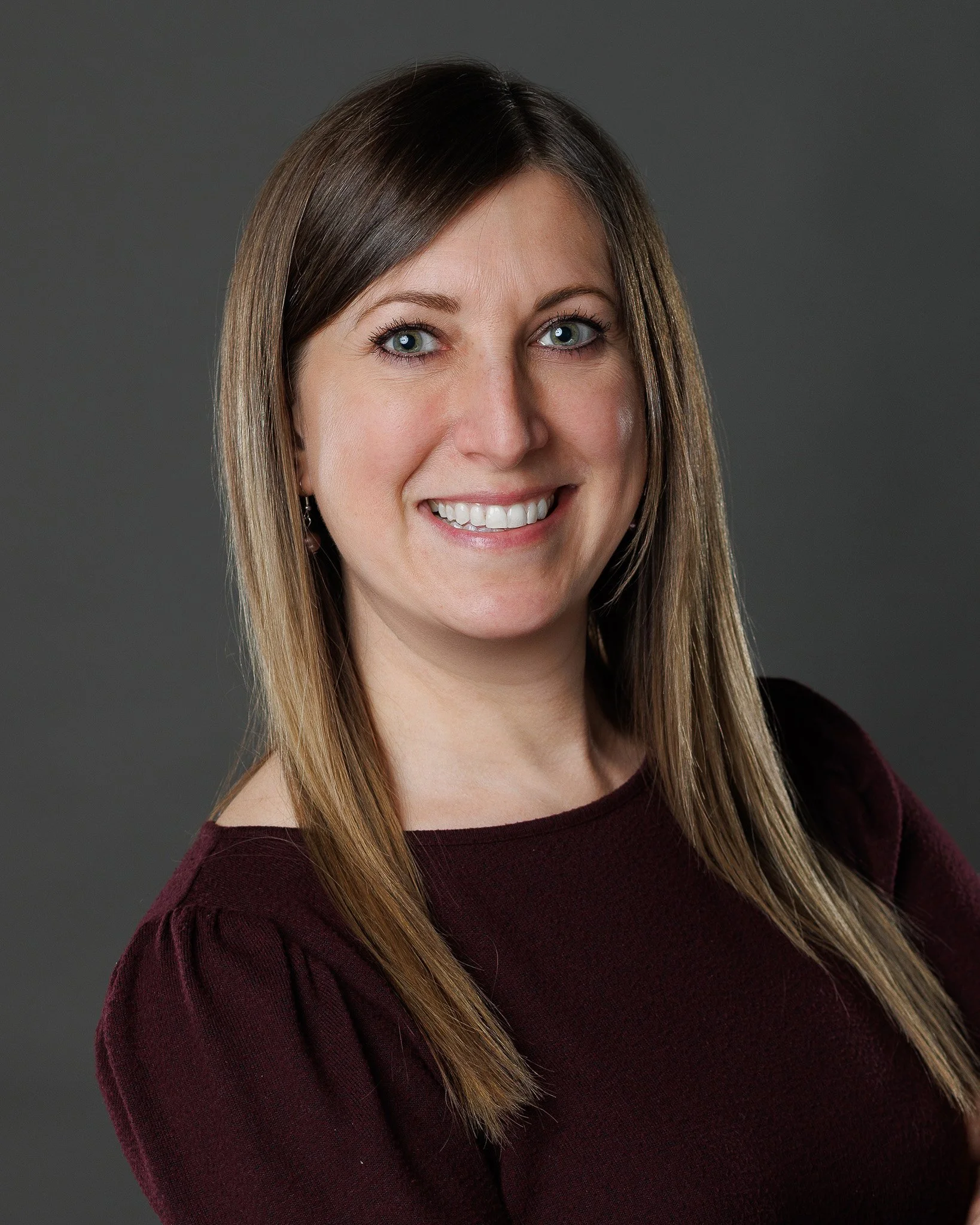 Corporate professional headshot of a female executive with expert lightng nd gray background