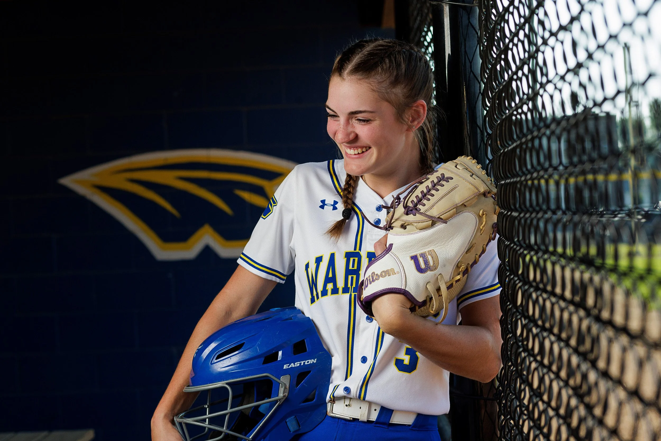 Softball pictures in the dugout for a Rice Lake High School senior girl by Seasons Photography.