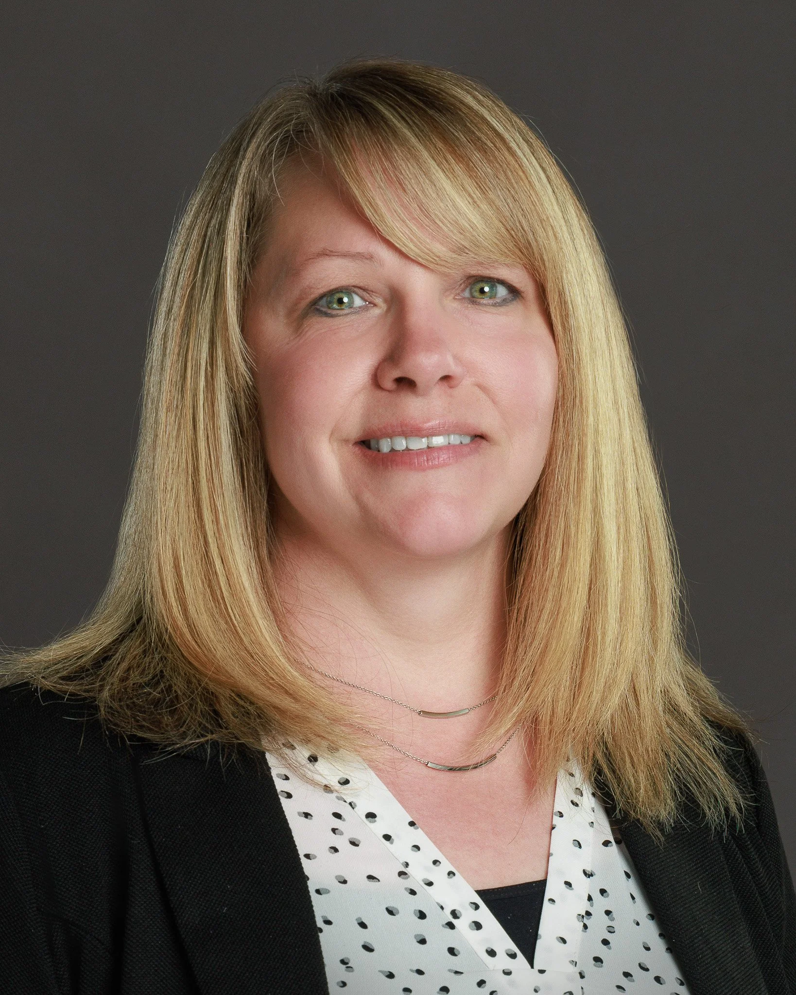 Business headshot for a women real estate agent featuring confident posing and professional lighting.