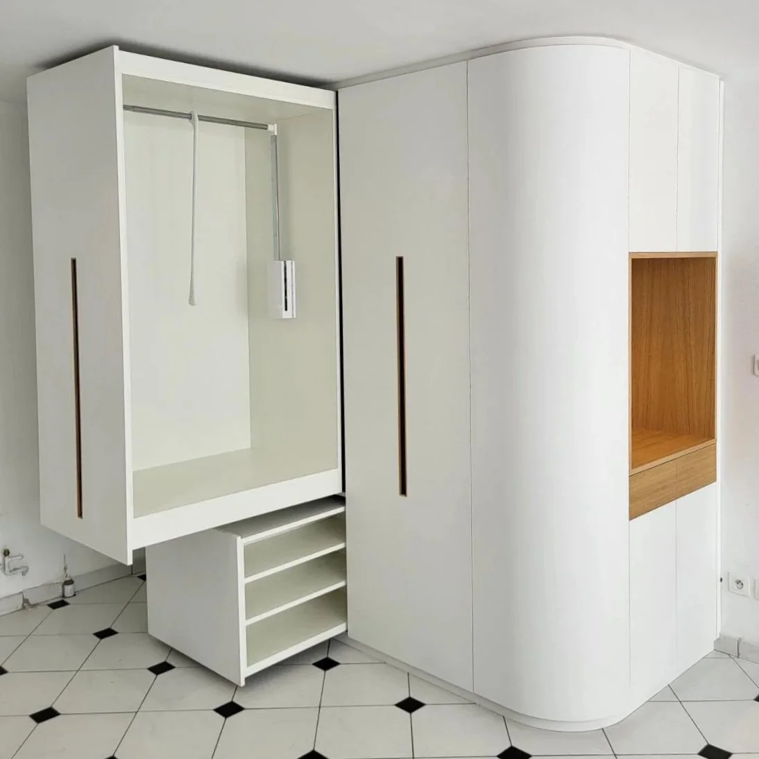 Meuble de rangement blanc intégré dans un mur avec un espace ouvert et des étagères en bois.