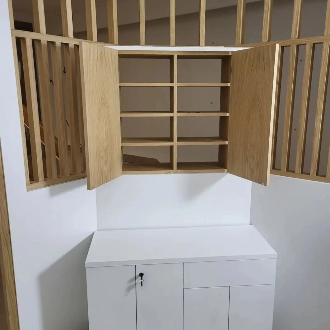 Meuble en bois blanc avec portes et serrure, fixé sous un meuble en bois avec portes vitrées, dans une pièce intérieure.