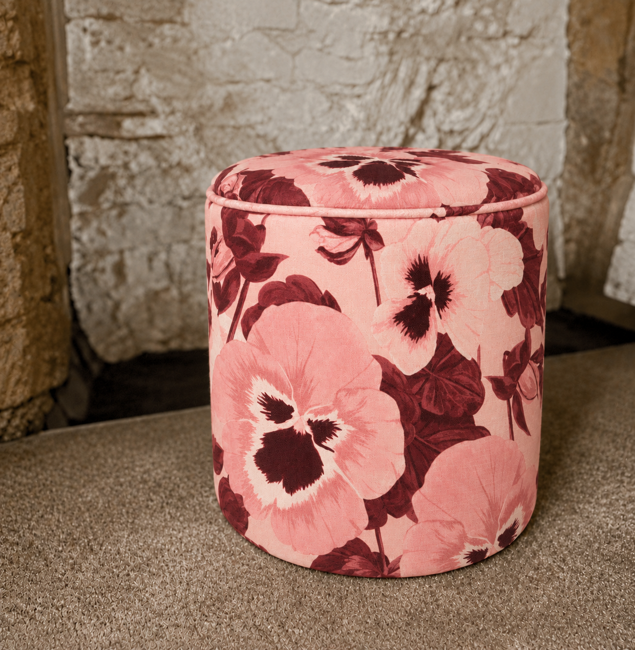 Pansy-print pouffe on rustic stone.png