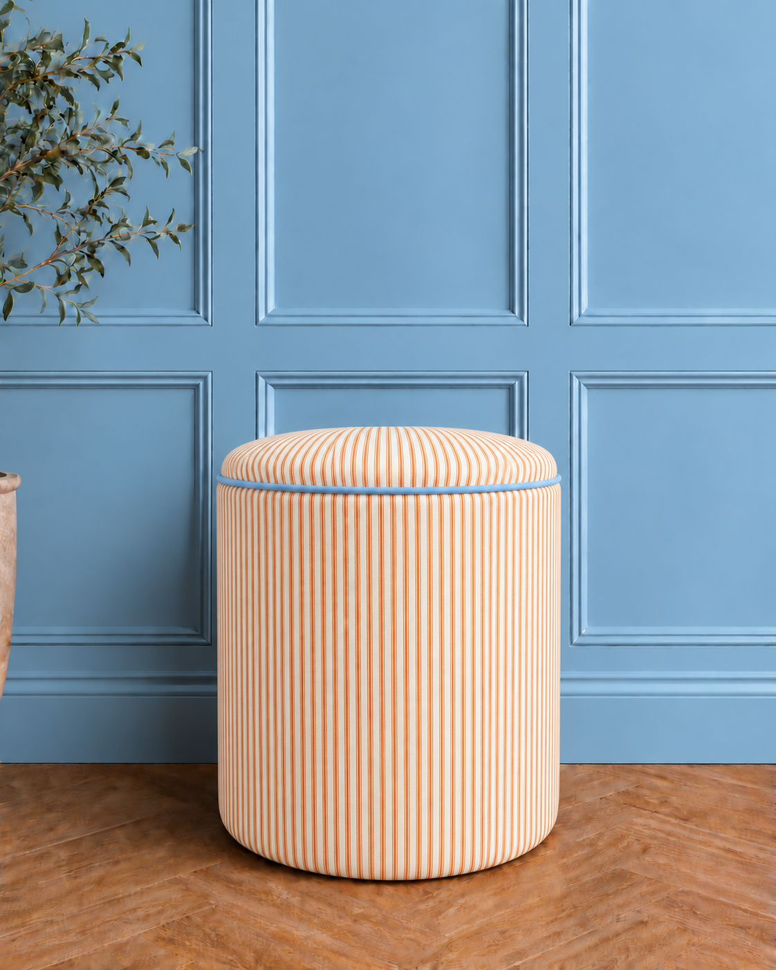 Orange striped pouffe in blue room.png