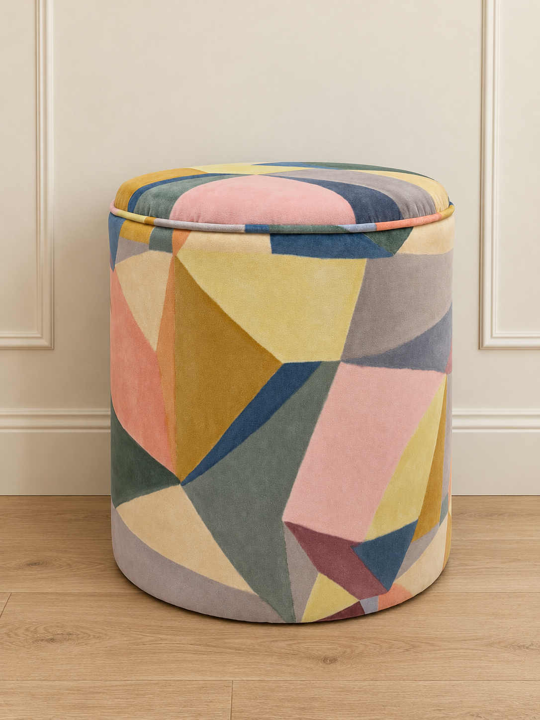 Abstract geometric pouffe against a cream wall.png