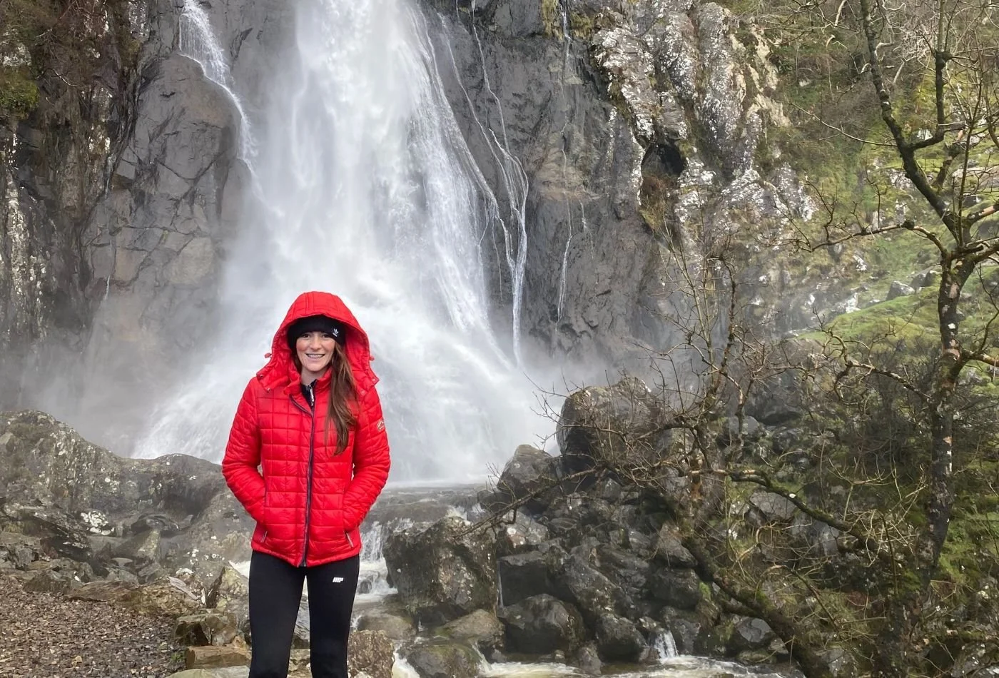 Woman stood in front of Aber Falls with red coat