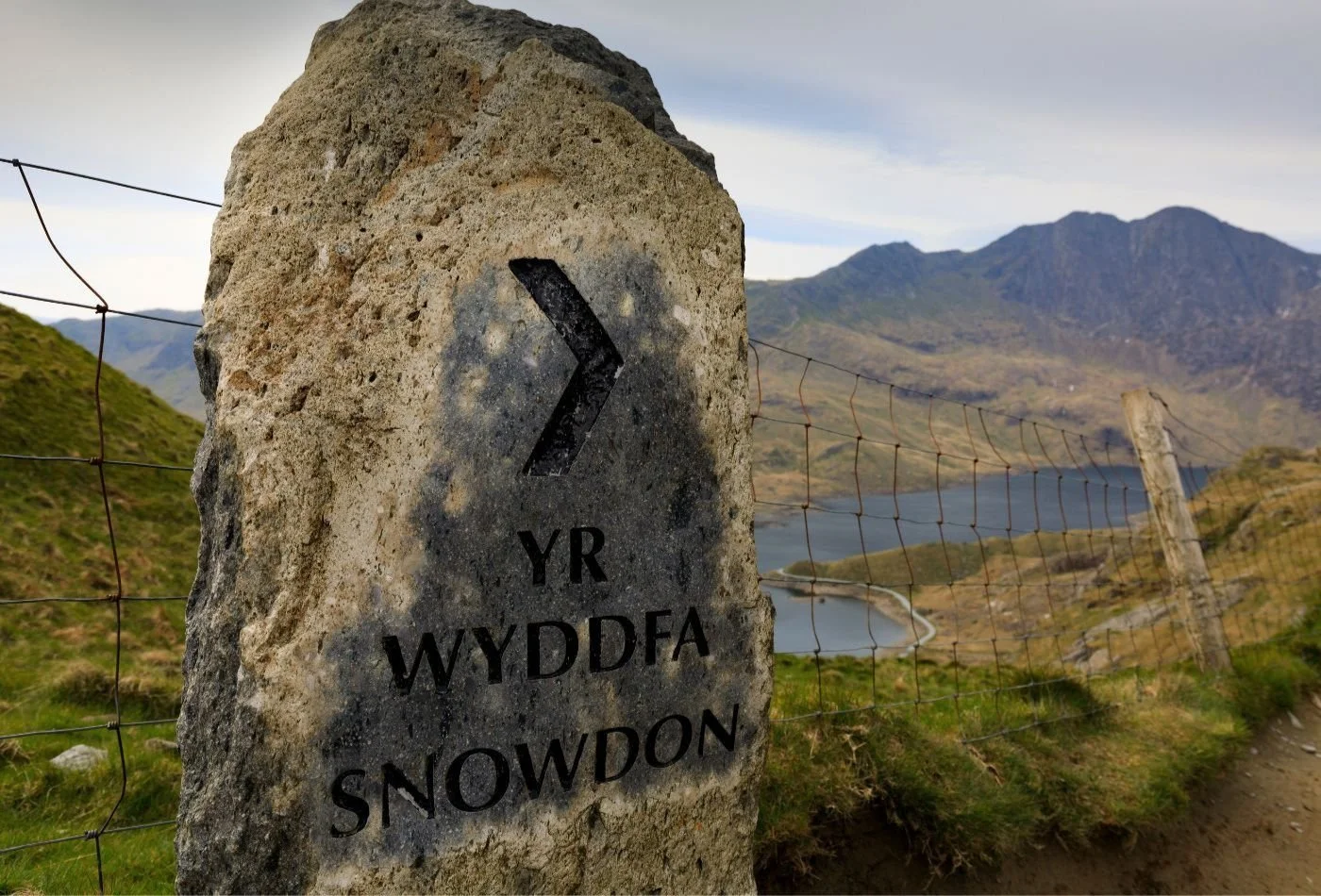 Views of Snowdon with a sign for ‘Yr Wyddfa’ in the foreground.