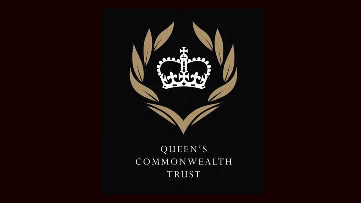 A black background with a gold laurel wreath surrounding a white crown, and the text "Queen's Commonwealth Trust" below.