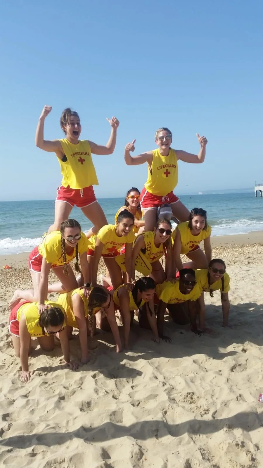 Inglis Netball Club players at Beach Netball 2019, wearing lifeguard outfits and forming a human pyramid.