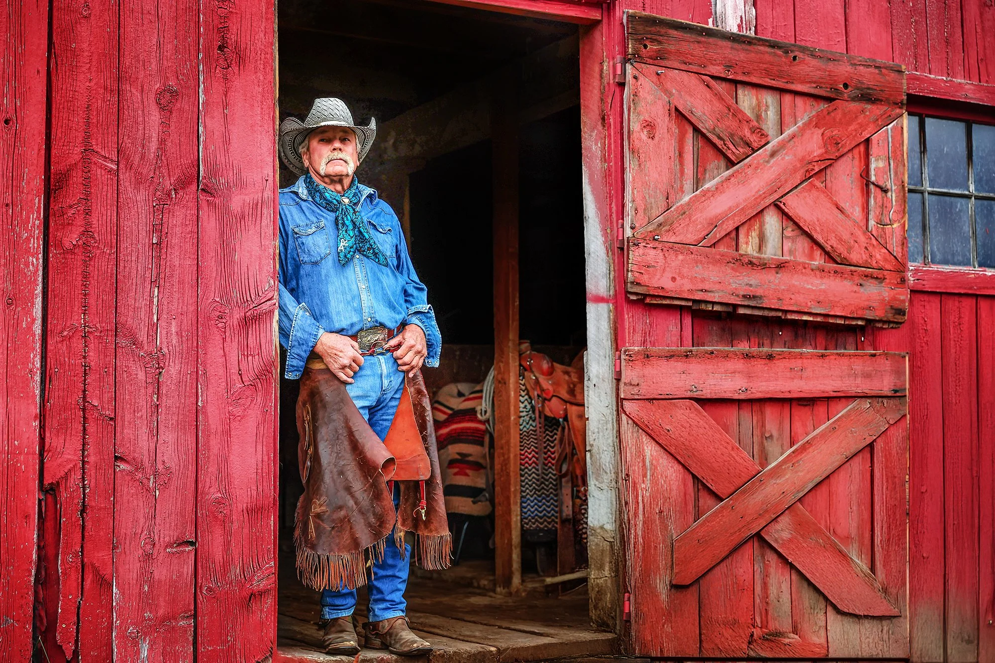Photographer photo of old cowboy standing in barn door