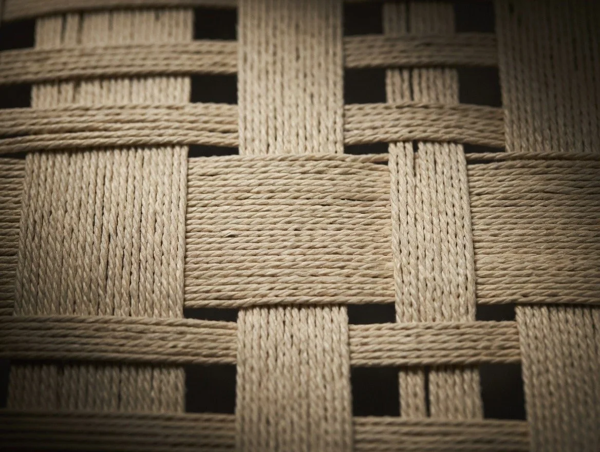 Close-up of a woven beige woven rope seat in Wooden Objex walnut chair. 