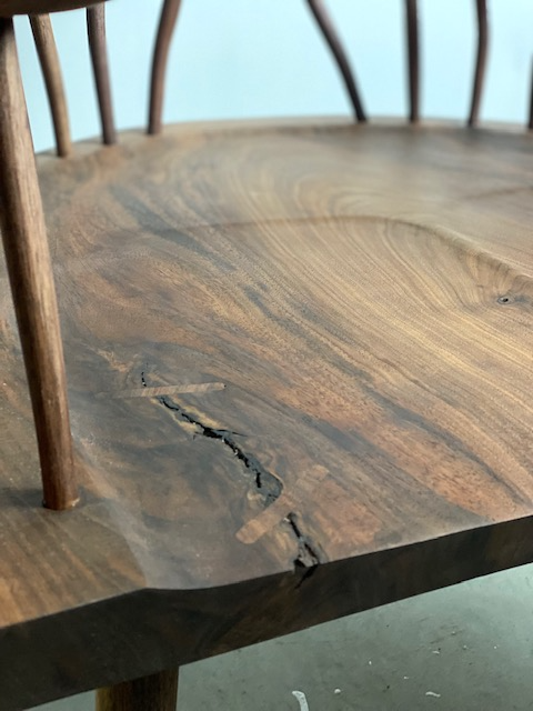 Close-up of a wooden chair with a cracked seat.