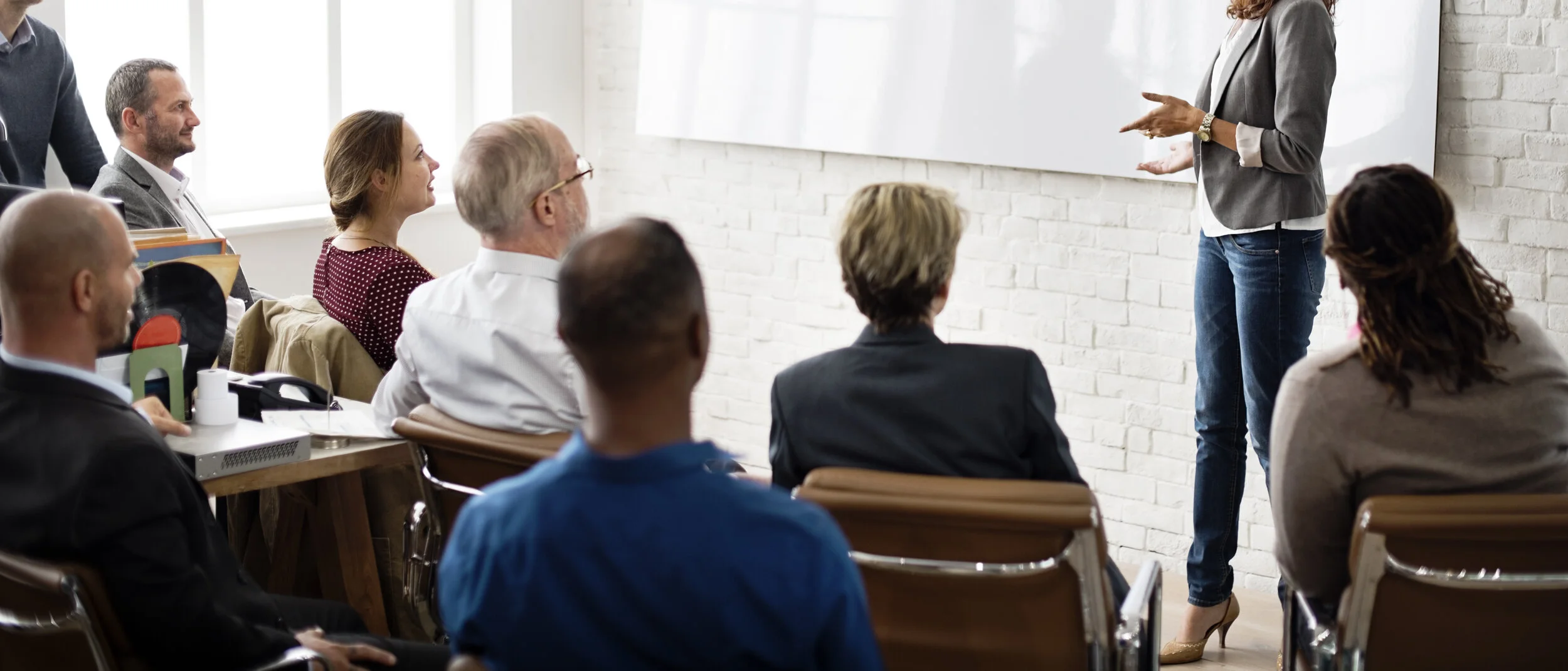 female presenting a training to people sitting in chairs