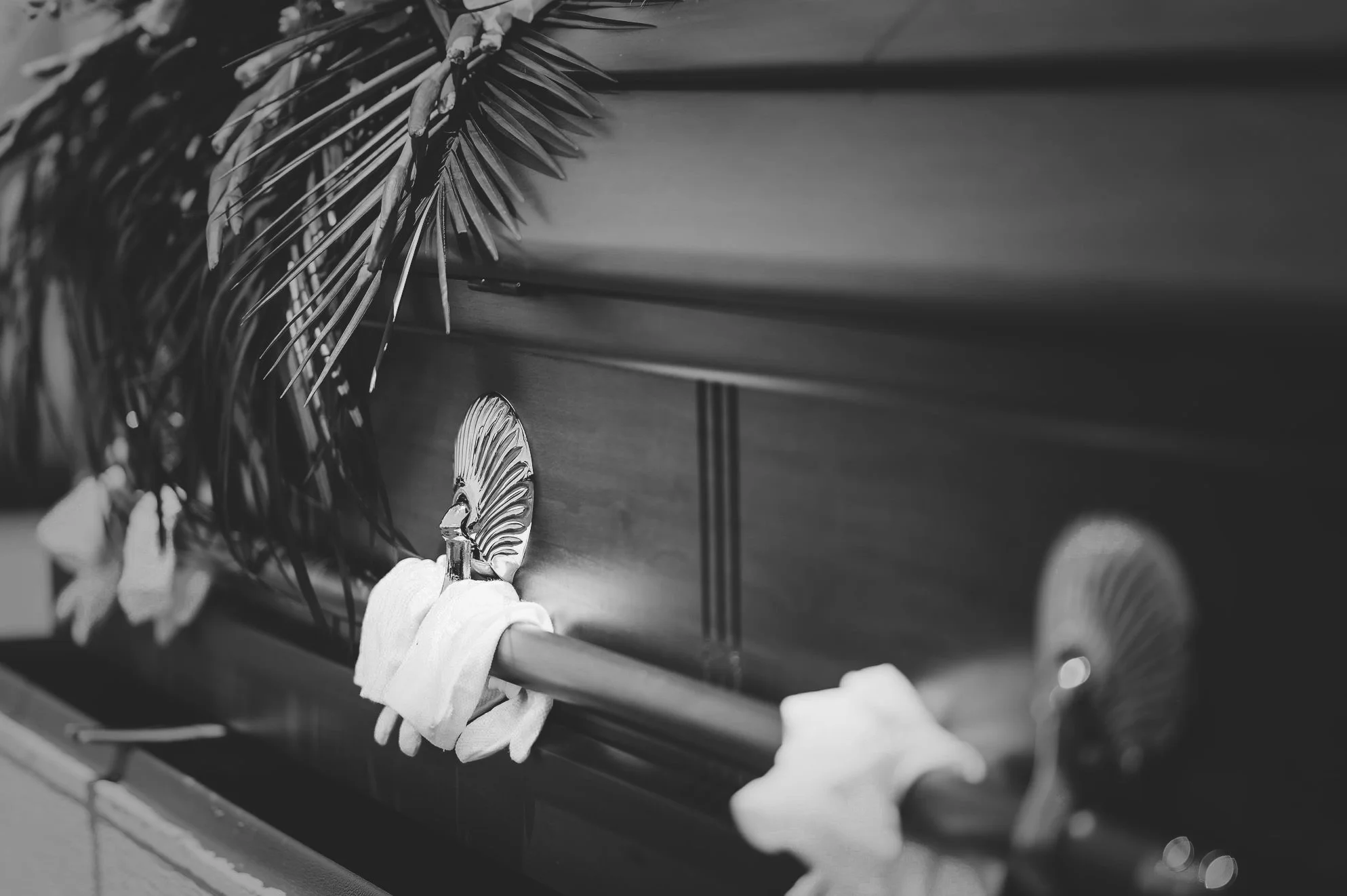 Pallbearer gloves resting on casket at funeral ceremony