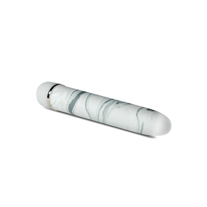 Vibe laying on its side at an angle pointing towards screen. Cylindrical vibe with tapered tip, white with gray marbling.