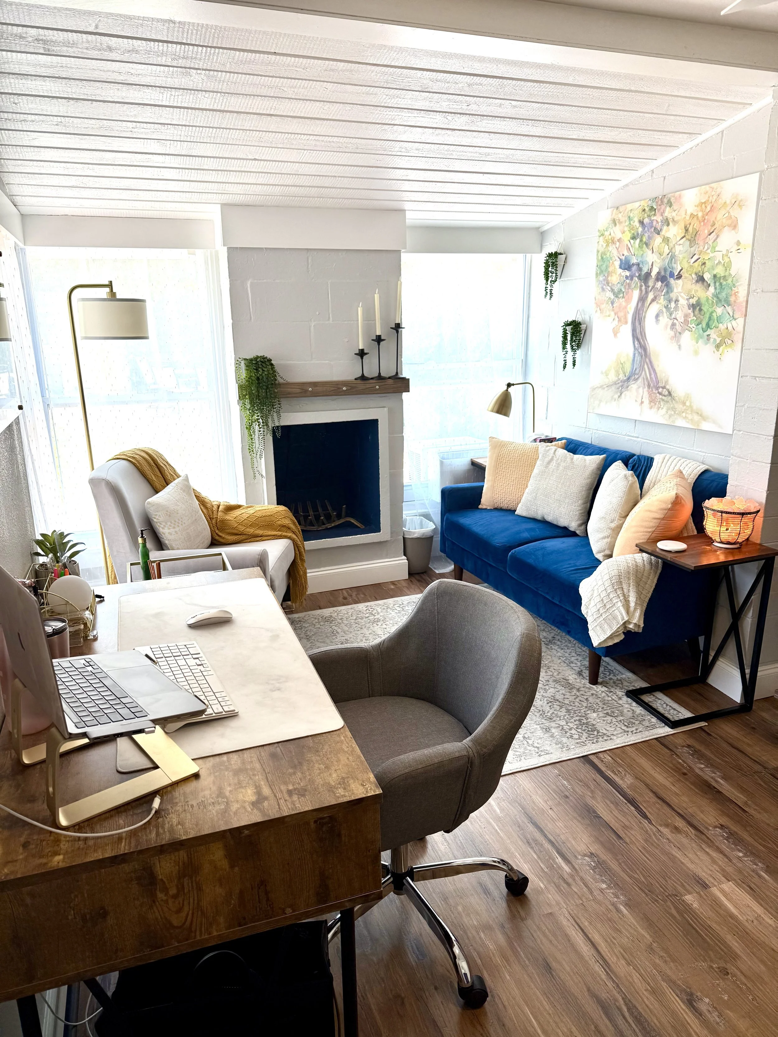 A cozy therapy office with a warm inviting feel. A safe space with large windows letting in natural light. Office is located in Orlando, FL and is associated with a mental health office offering tele therapy and in-person sessions.