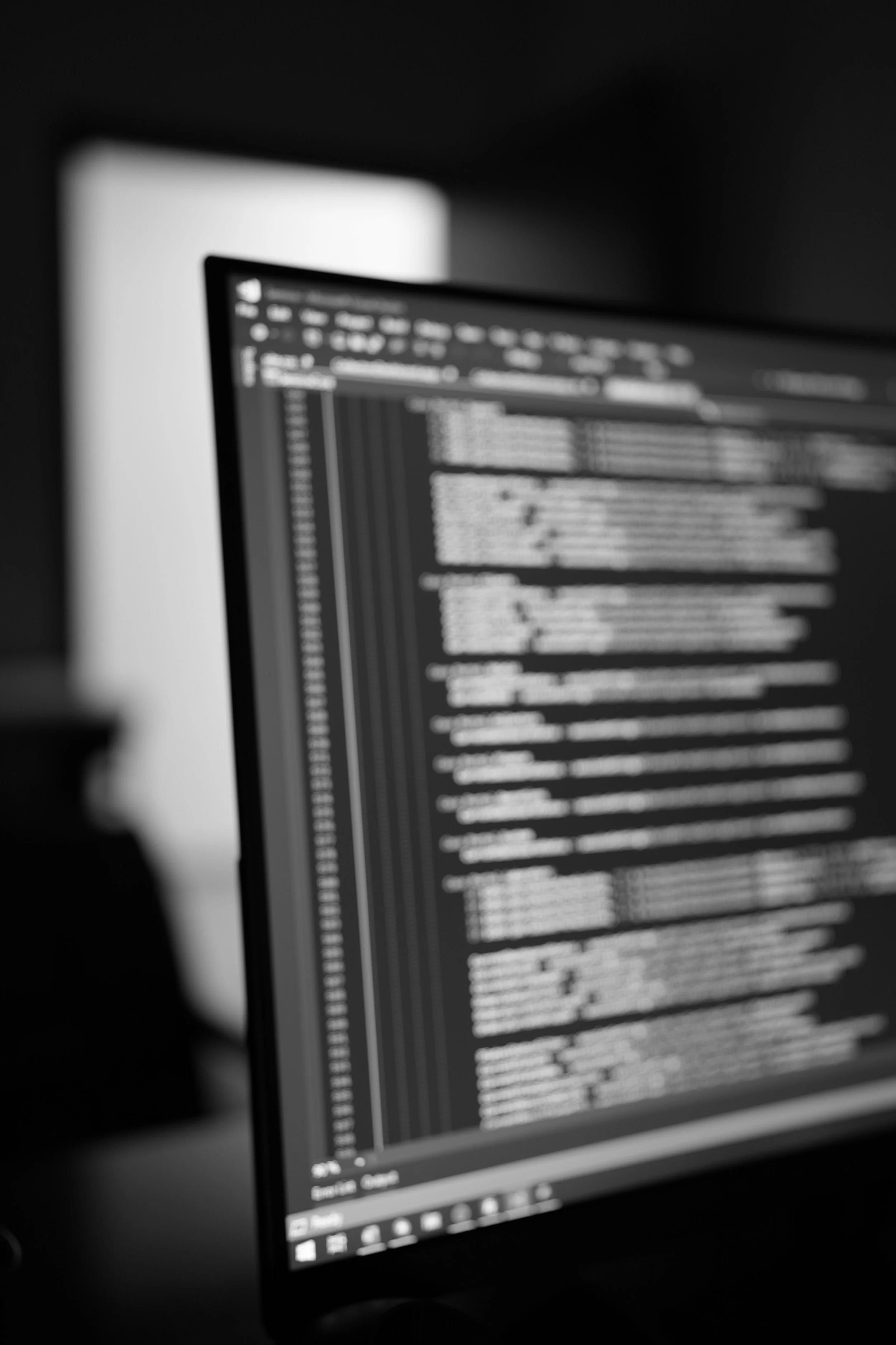 A computer monitor displaying lines of code on a dark background in a dimly lit room.