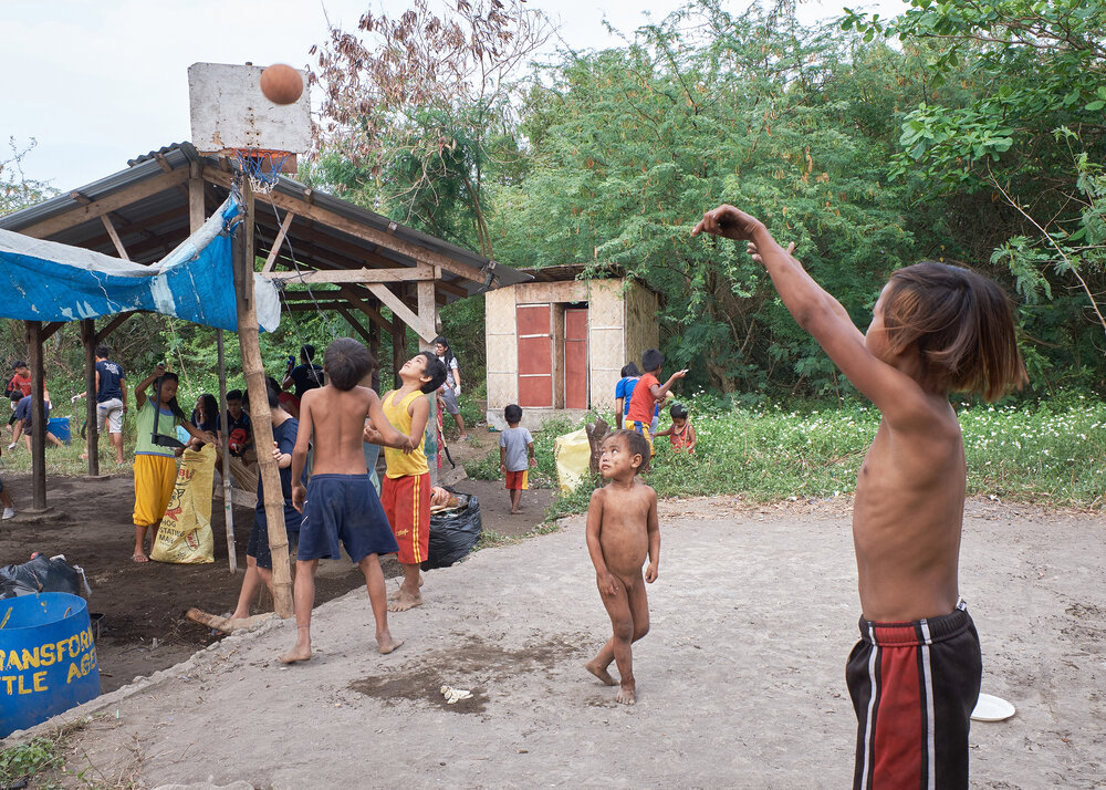  Boys playing basketball. There’s an outhouse&nbsp;recently built by 3G HMI behind the trees. Sanitation is improving in the village. 