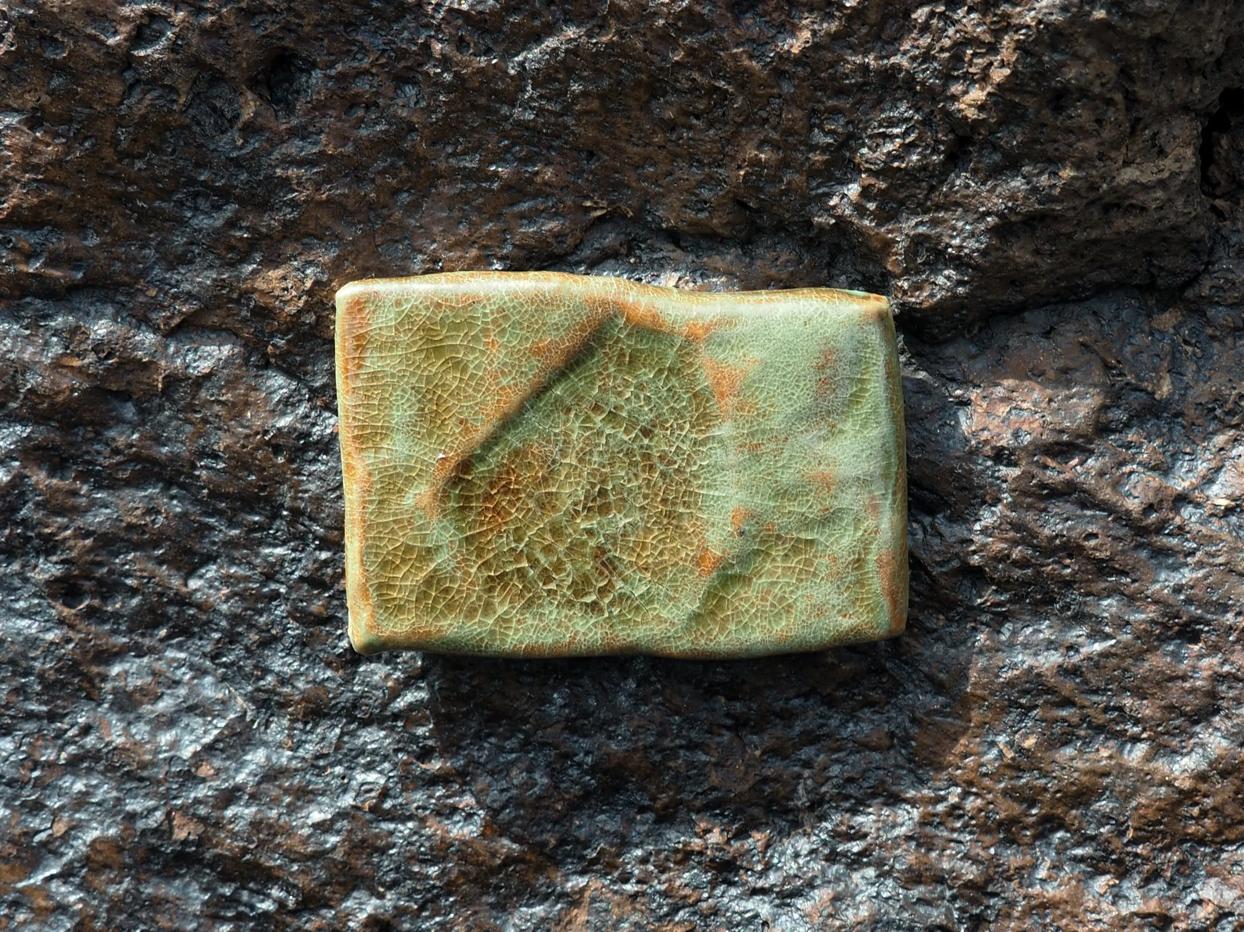 Green papier-mâché sculpture on dark stone background