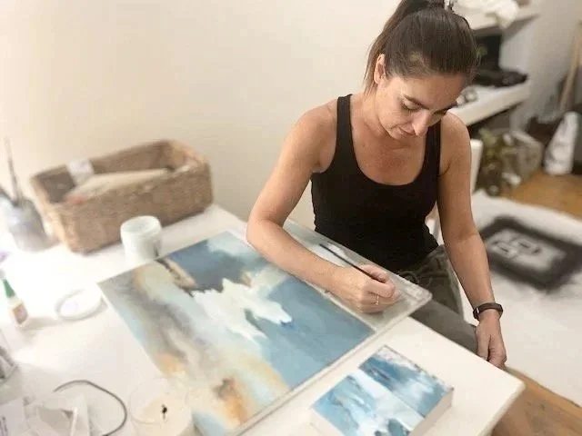 Daniela Milinkovich, the artist, in her art studio with painting supplies, focused on her artwork.