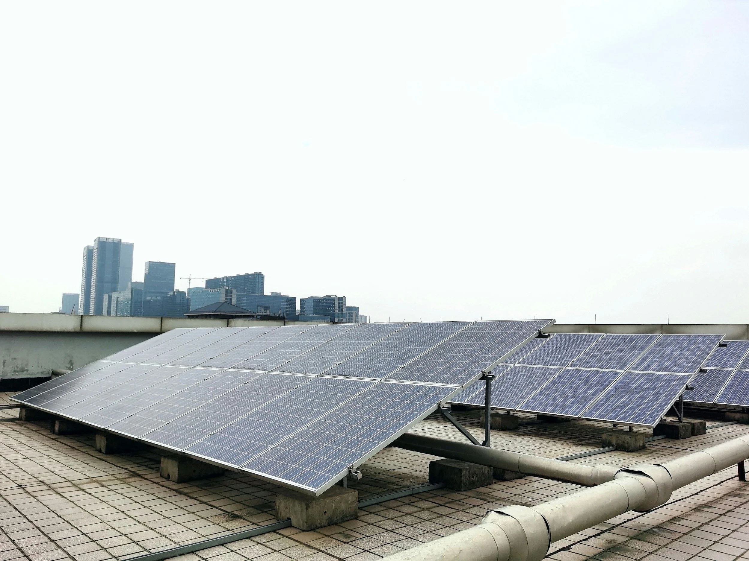 Solar panels installed on a rooftop with a city skyline in the background.