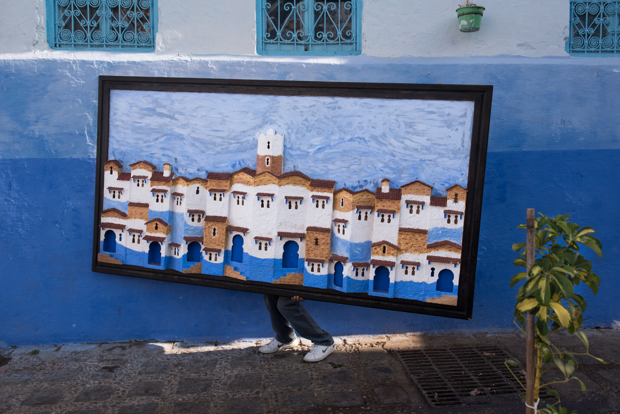    Morocco - Chefchaouen     Man carrying a large painting of Chefchaouen 