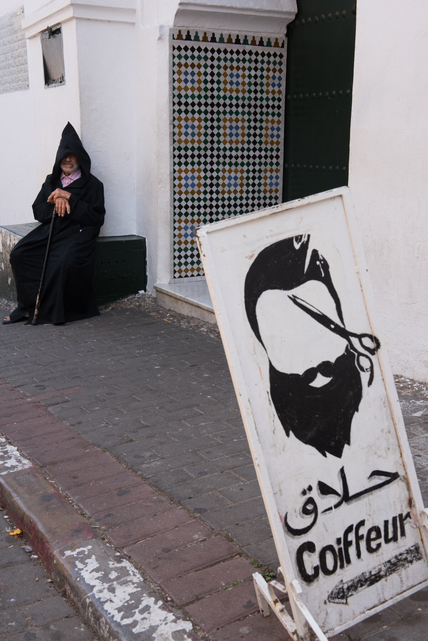    Morocco - Tanger     Old hooded man sitting outside of mosque 