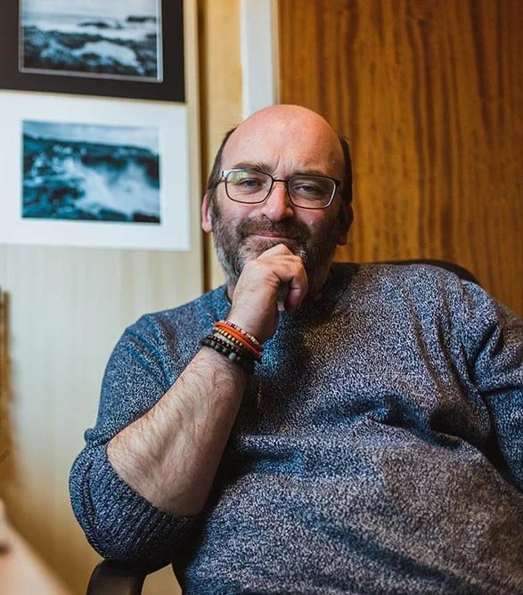 Hand resting on chin smiling at camera.