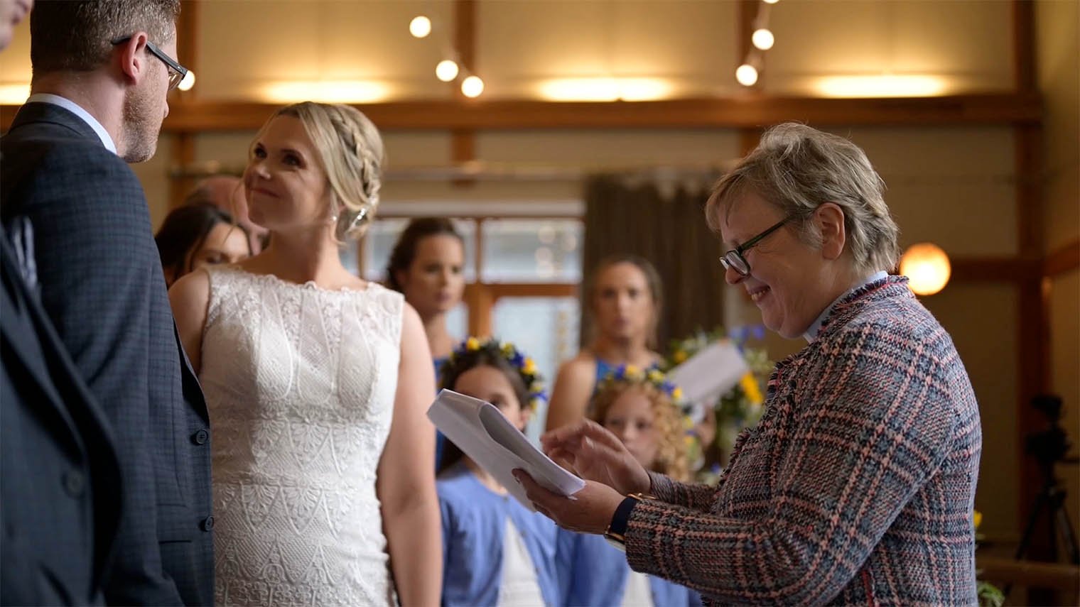 Minister conducts religious ceremony as bride looks at groom.