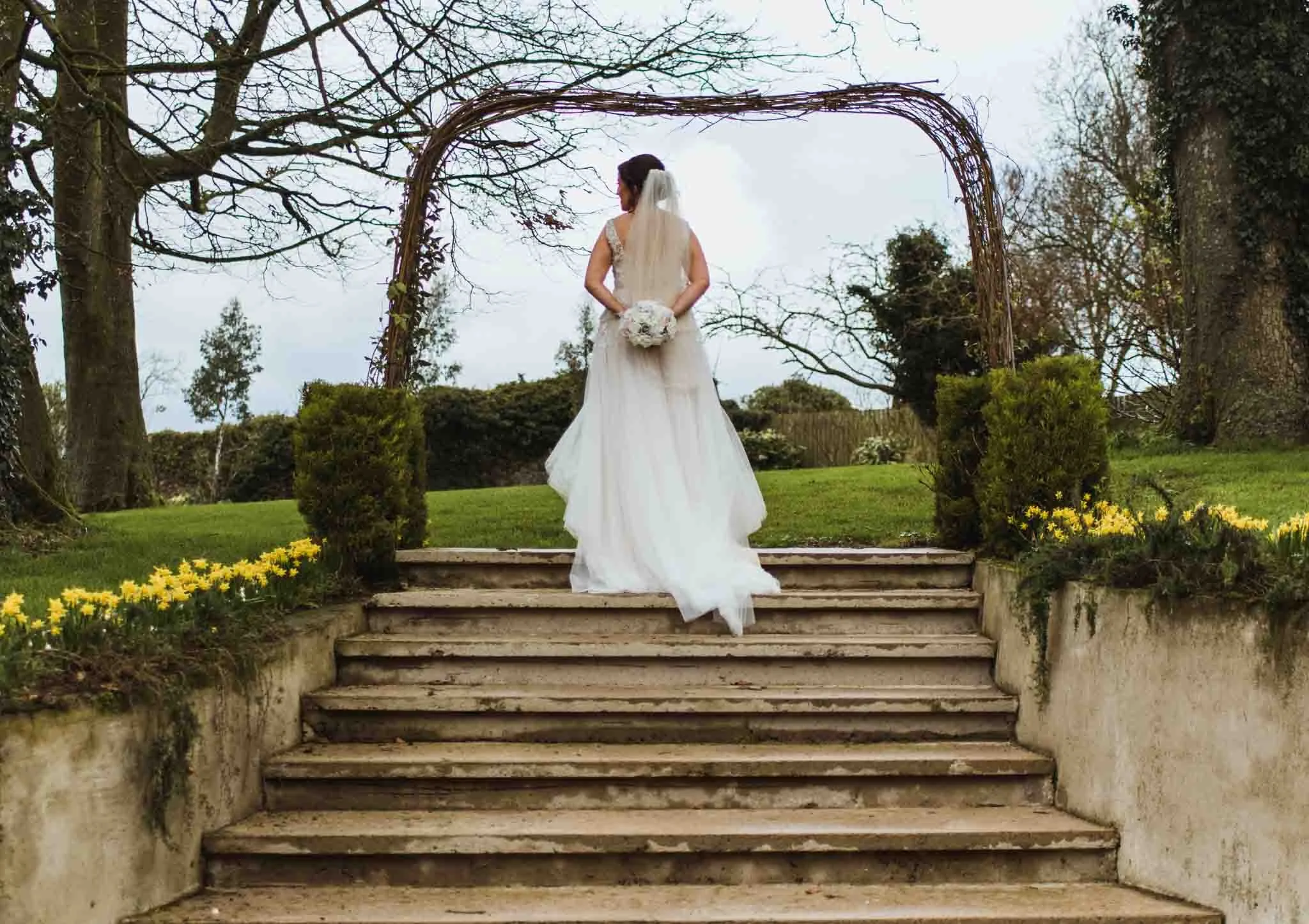 Bride with bouquet photographed from the back at the top of the steps in Gracehall.