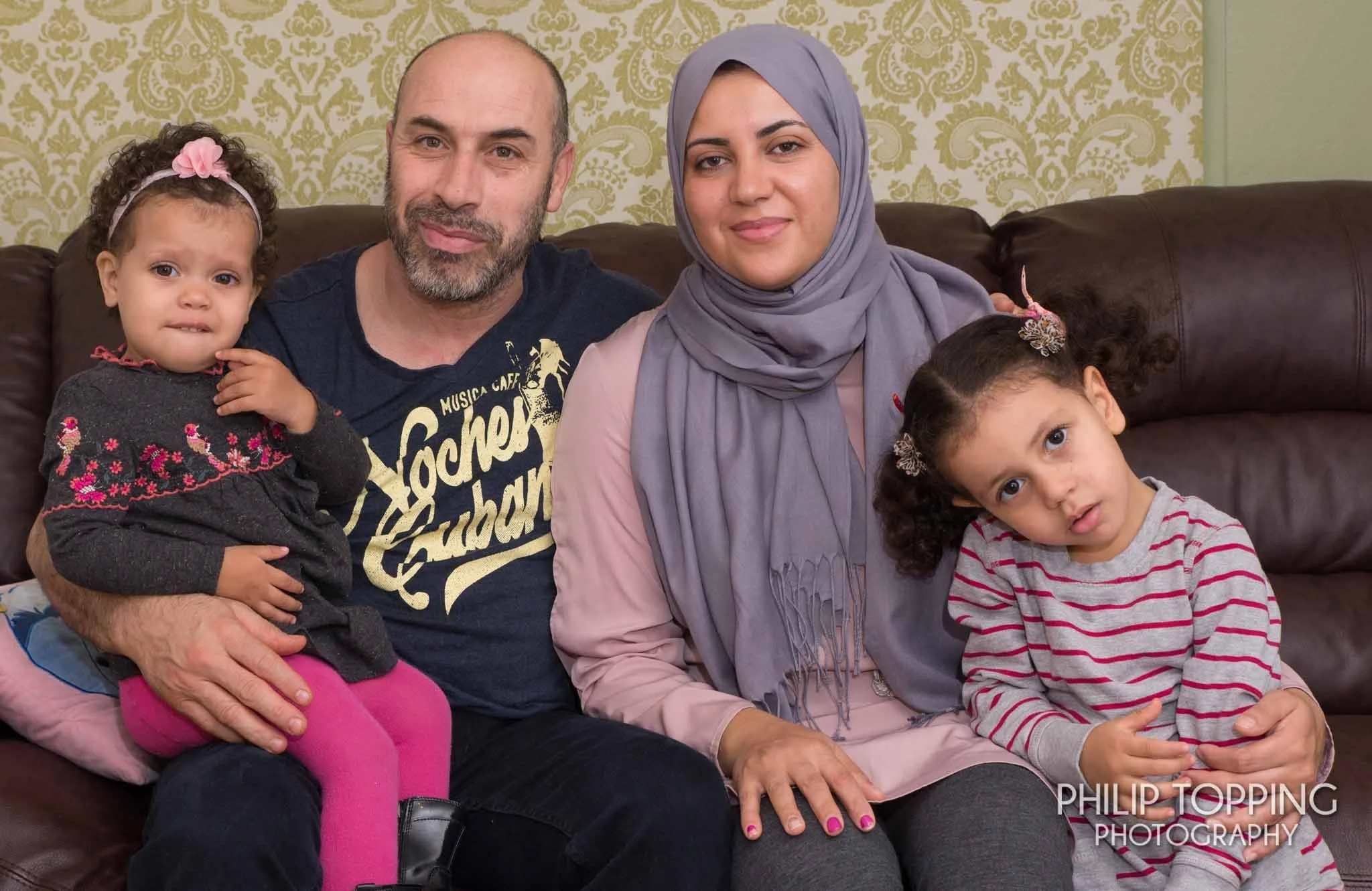 Family photo in the home on the couch with parents and two kids.