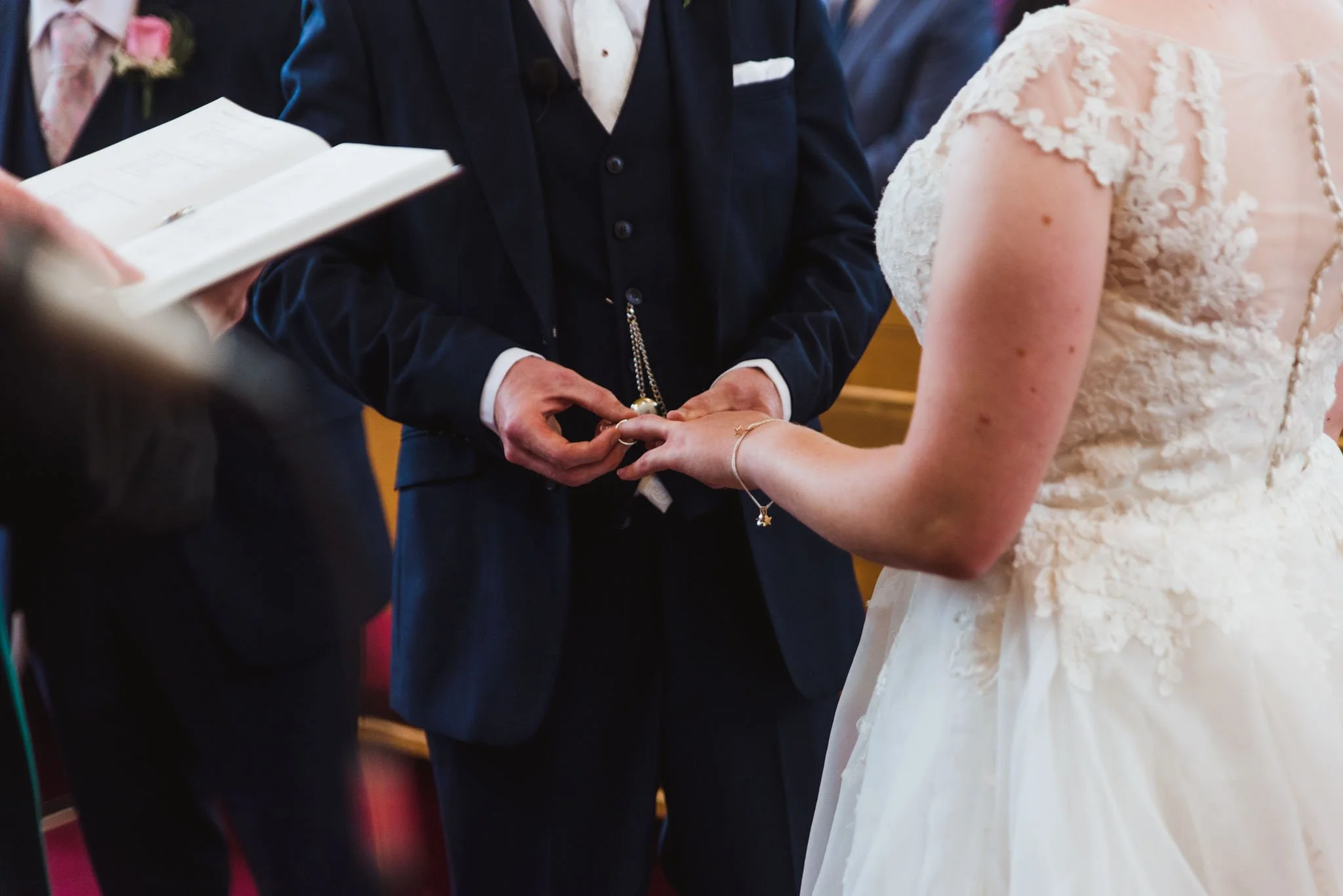 Close-up of the groom putting on the bride's ring.