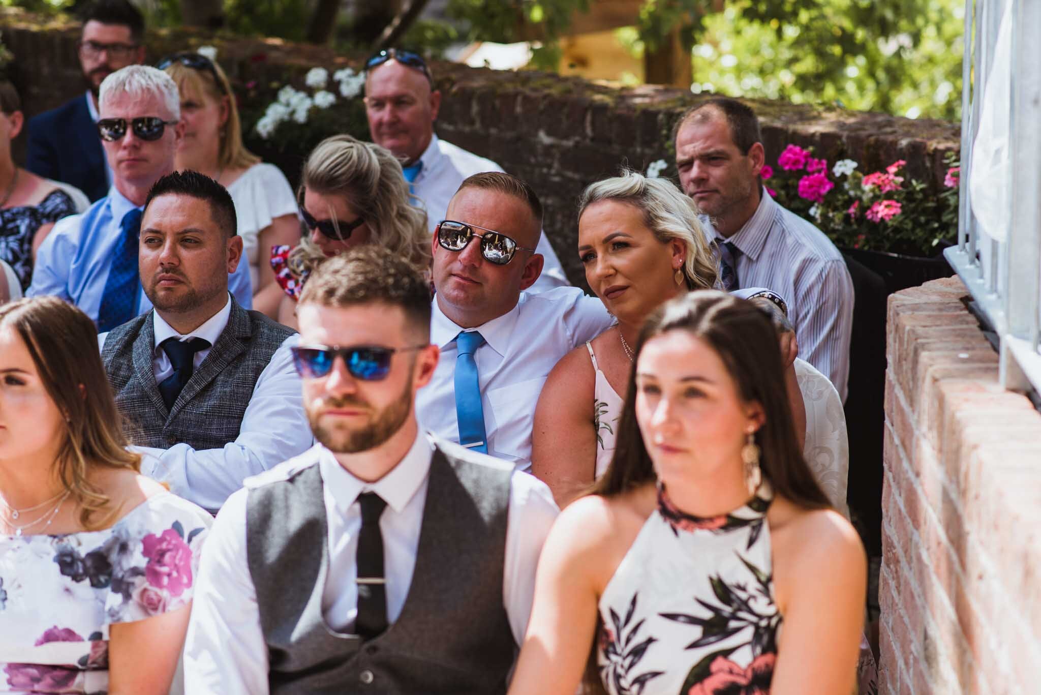  Guests some with sunglasses on a hit summer’s day in Templepatrick wedding. 