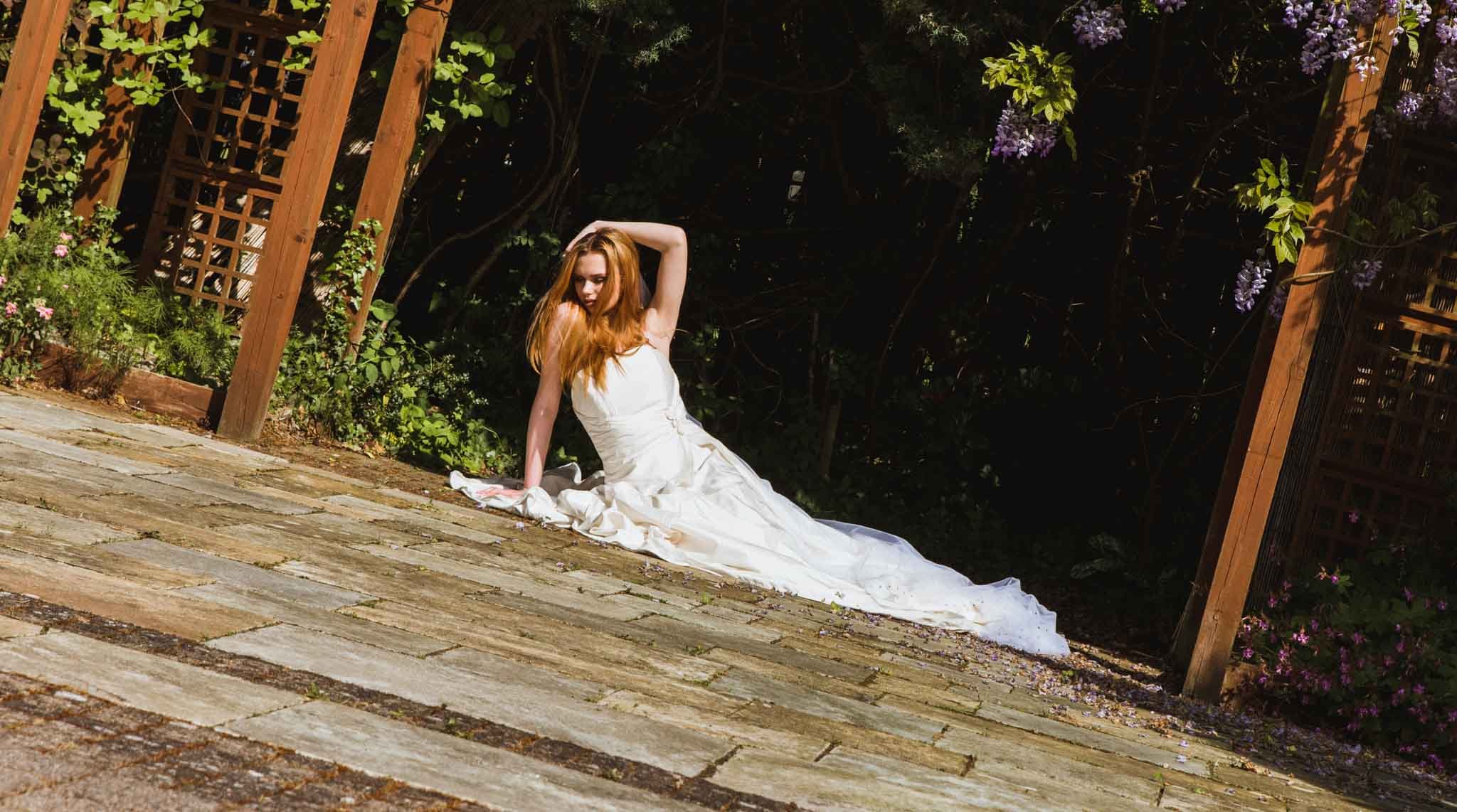  The bride is at the back of the gardens lying on the ground in a dress. 