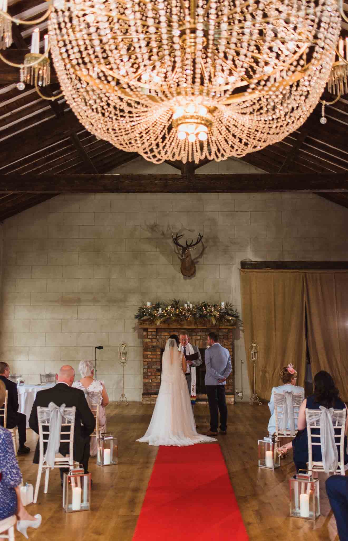  Bride and groom at end of red carpet under the large chandelier in a ceremony in this Lurga in this venue. 