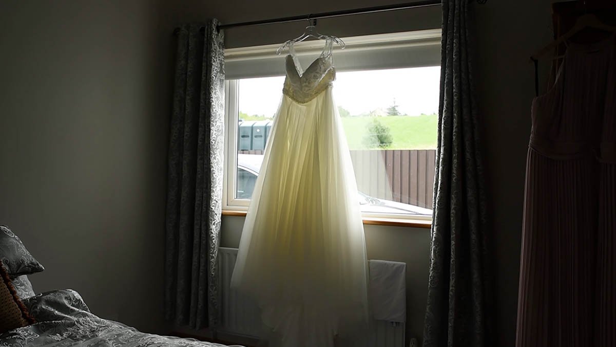  Brides dress hanging up at window 