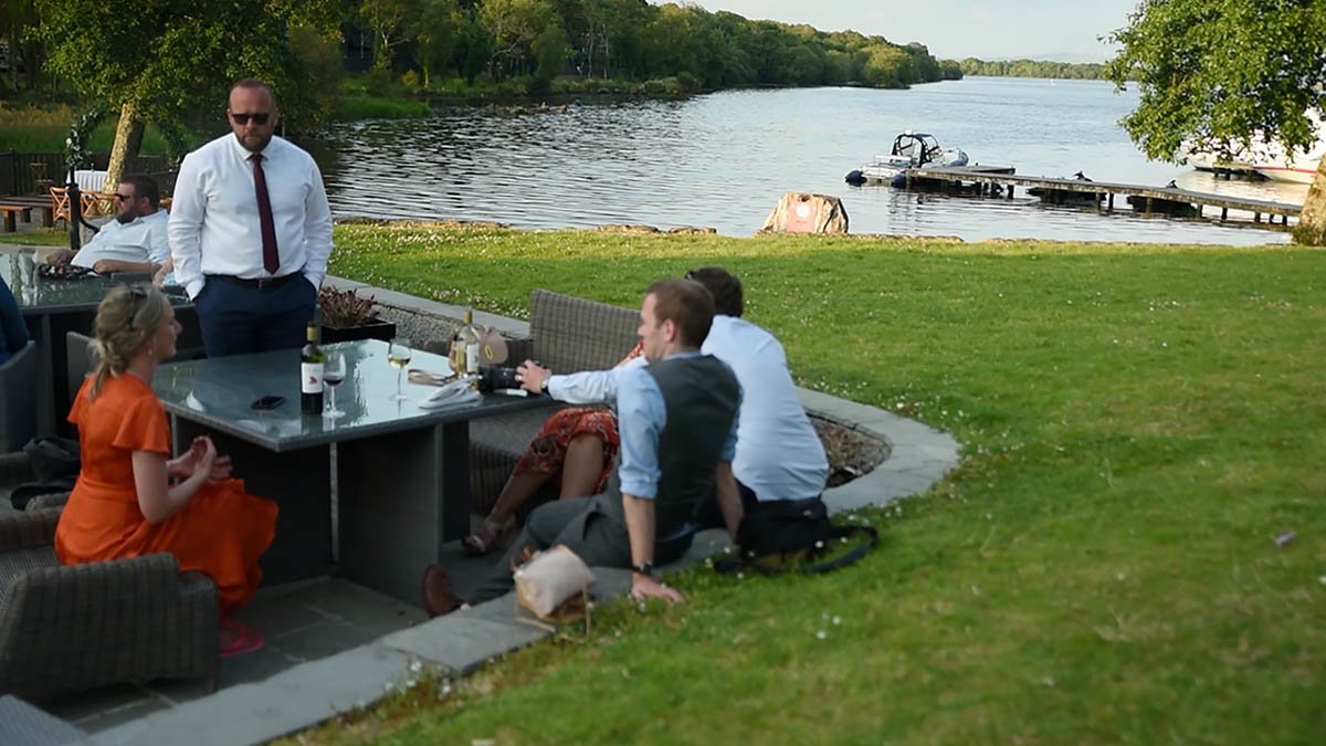  Guests relaxing outside by the shore with boats in the distance showing what a beautiful place Lusty Beg Island is. 