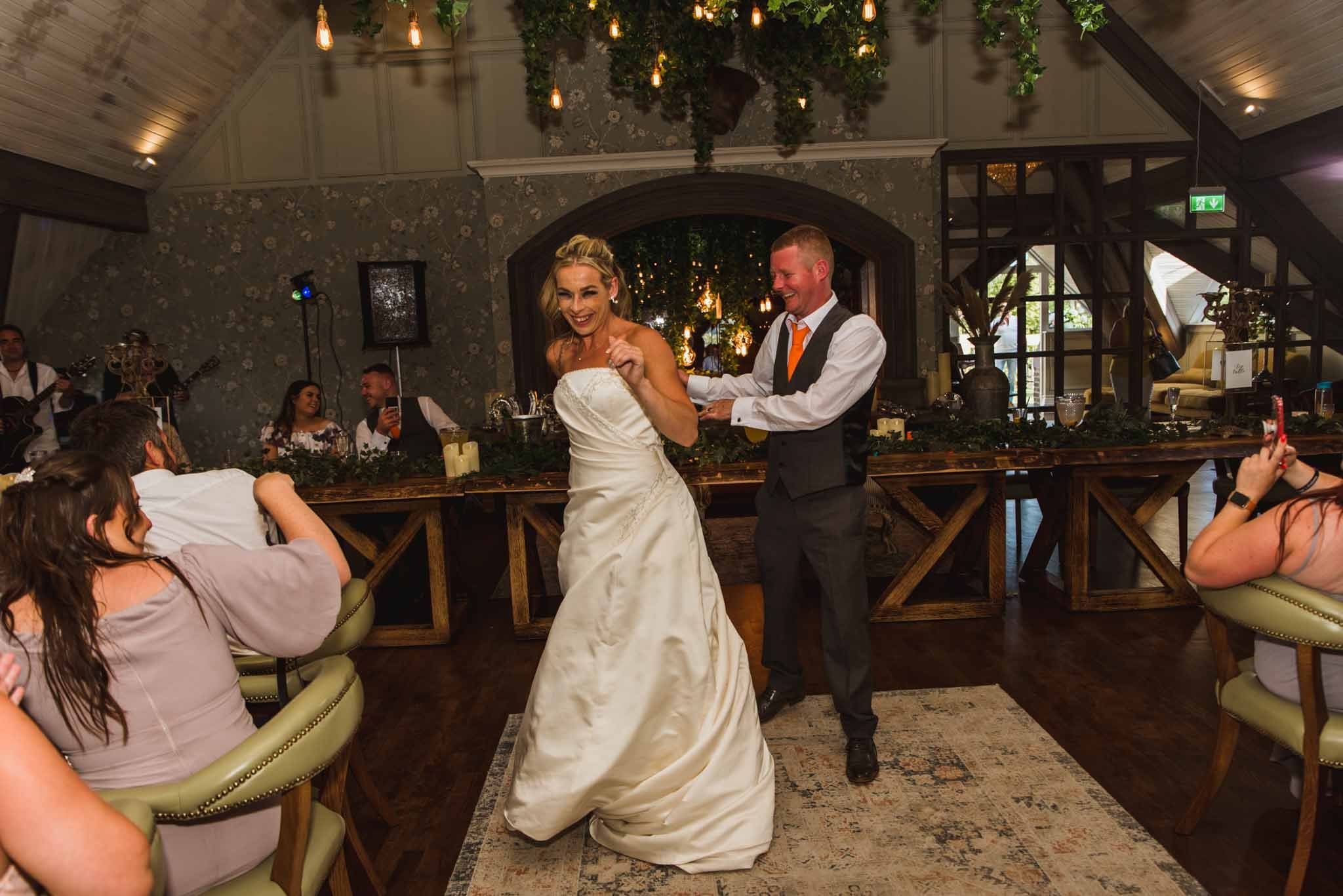  The bride and groom are in the middle of the room for their first dance on the large rug while everyone watches. 
