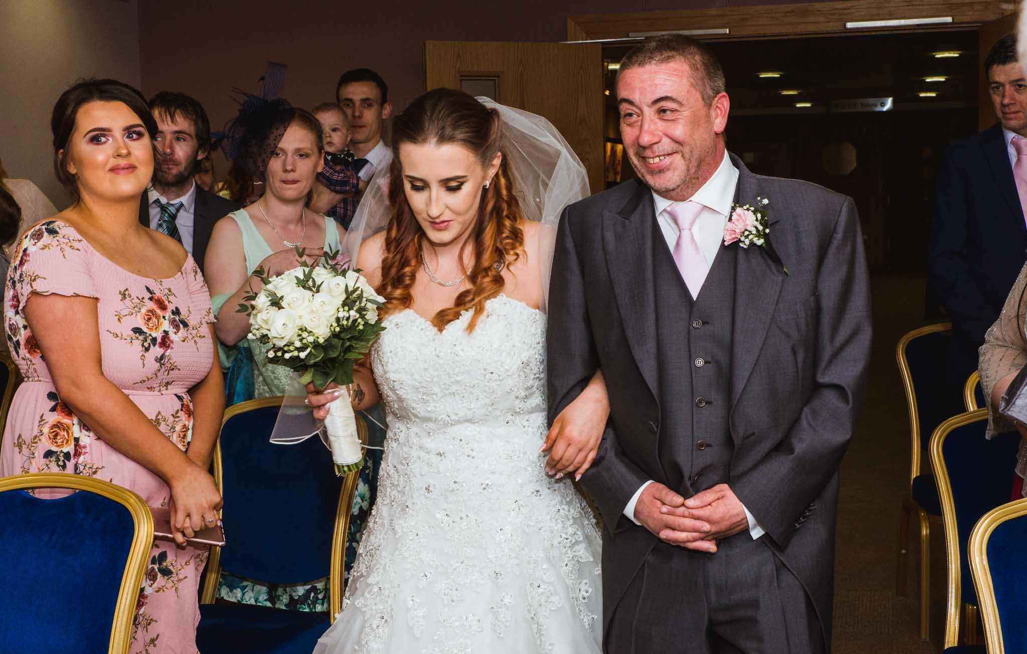  Bride with the father walking down the aisle at a ceremony in Craigavon Civic Centre located beside the lakes. 