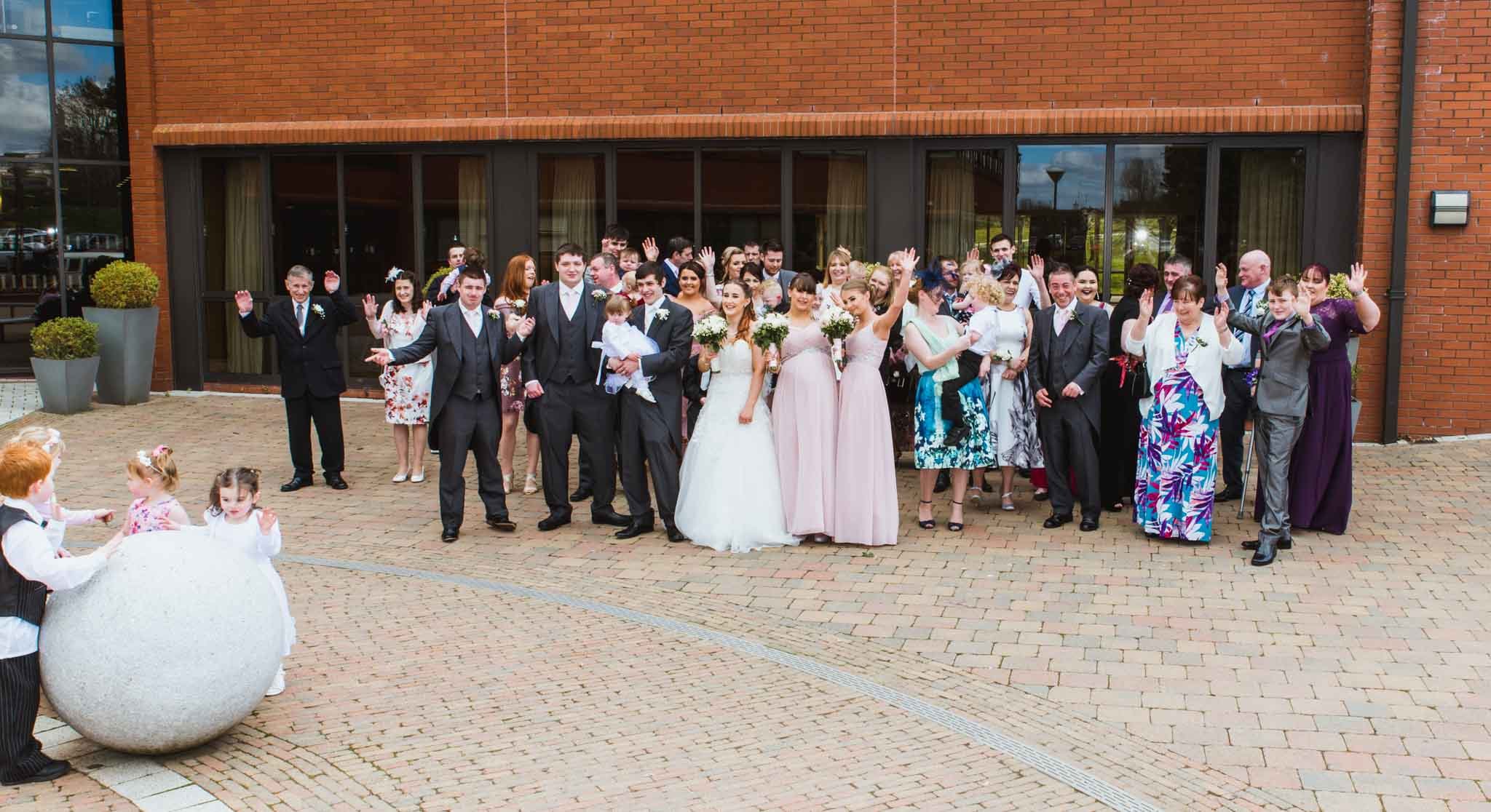  Group photo after the ceremony in front of the Civic Centre building with kids beside a round stone in the foreground. 