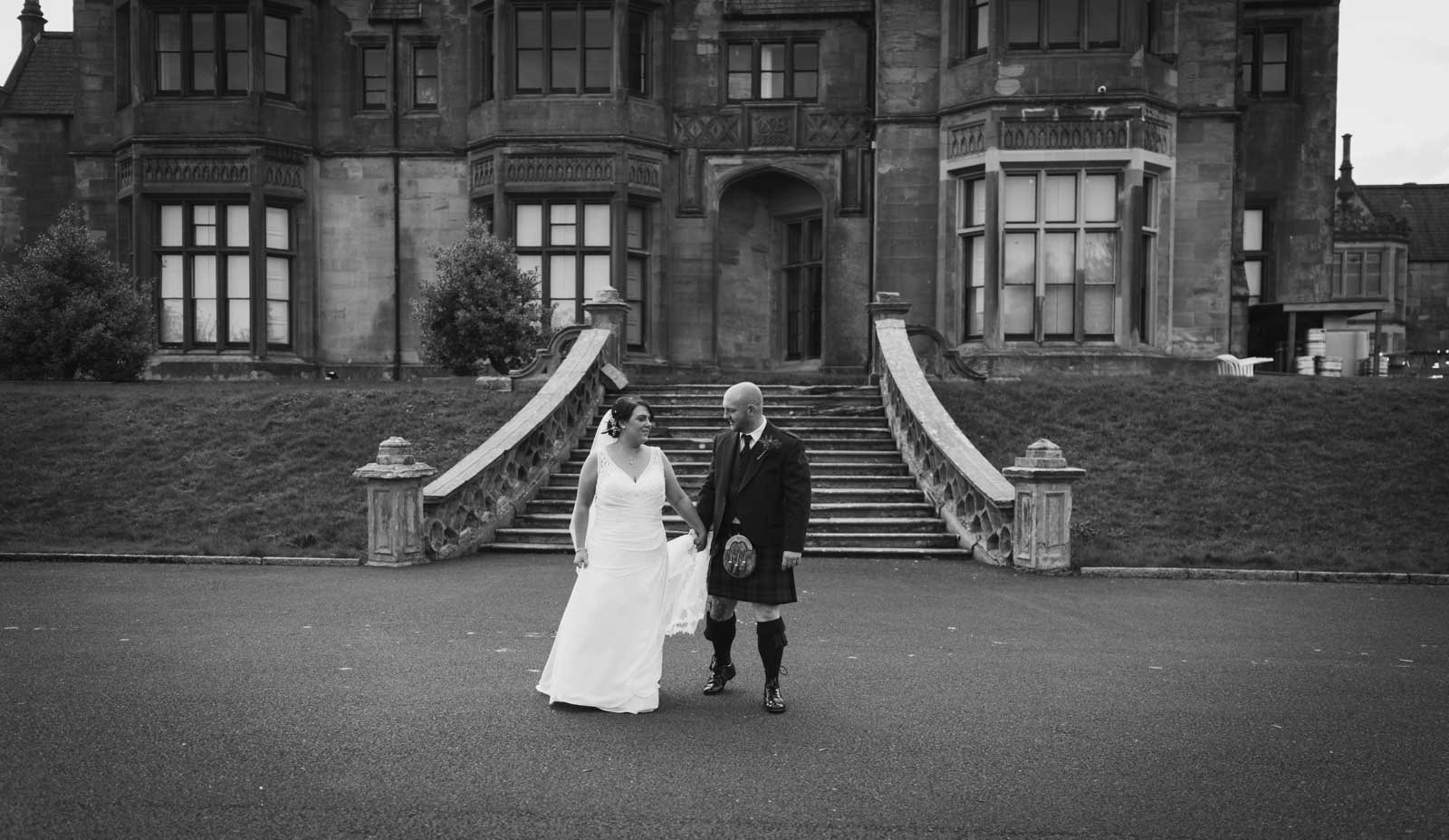 Bride and groomw walking away from  Brownlow Castle steps around the side of the building. 