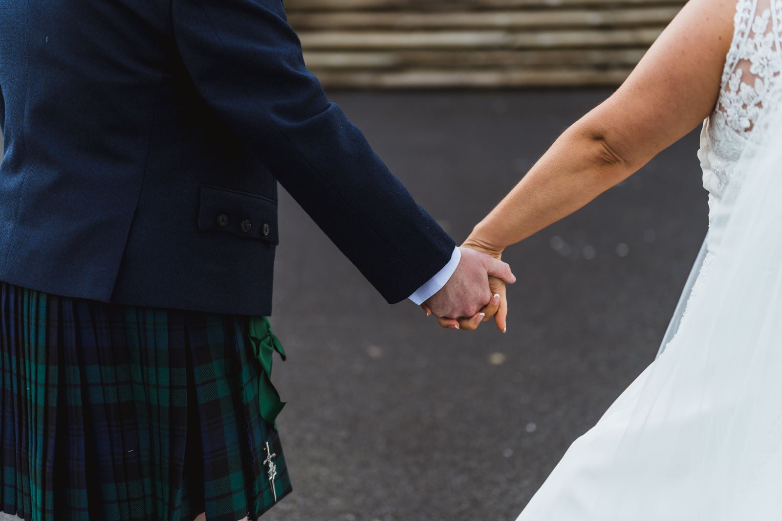  Close-up of a married couple holding hands photographed from behind walking towards steps. 