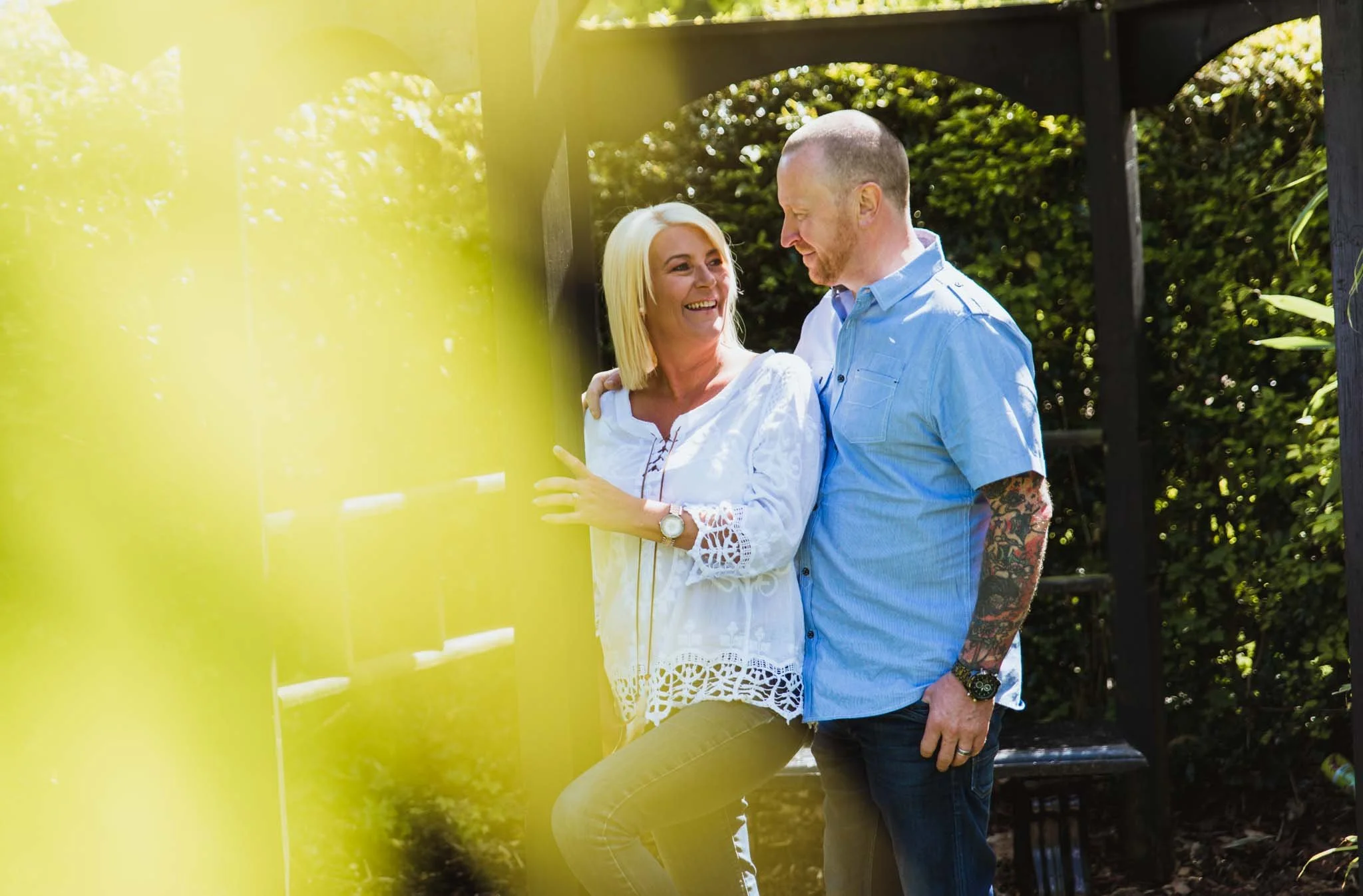  A couple under hit, looking at each other in love with yellow leaves blurred out in the foreground. 