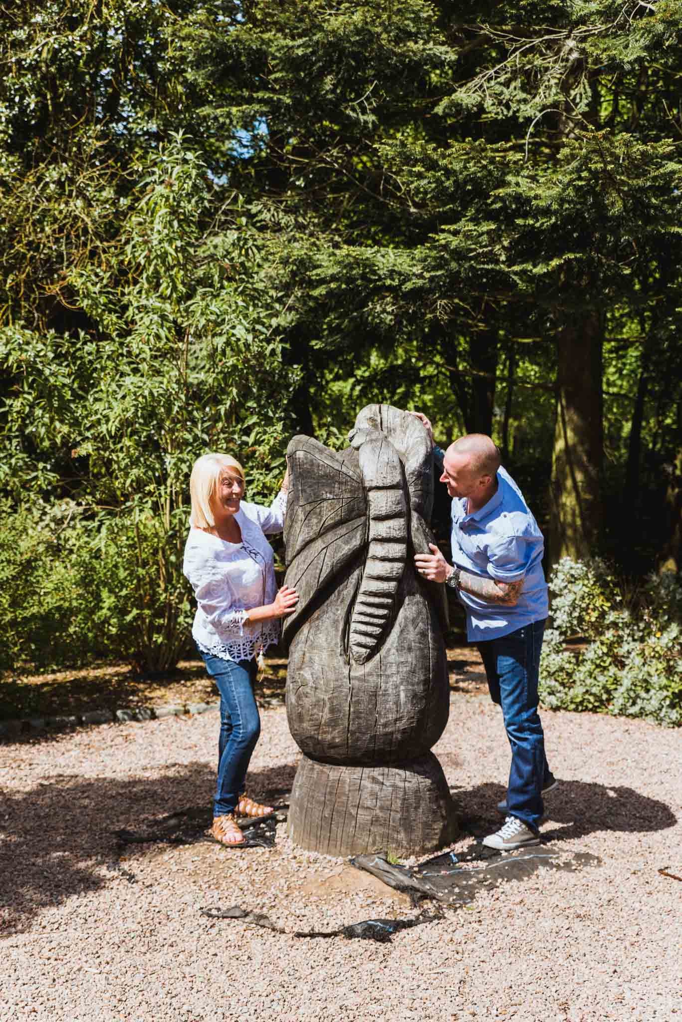  Wider photo of the couple hiding behind a carved sculpture. 