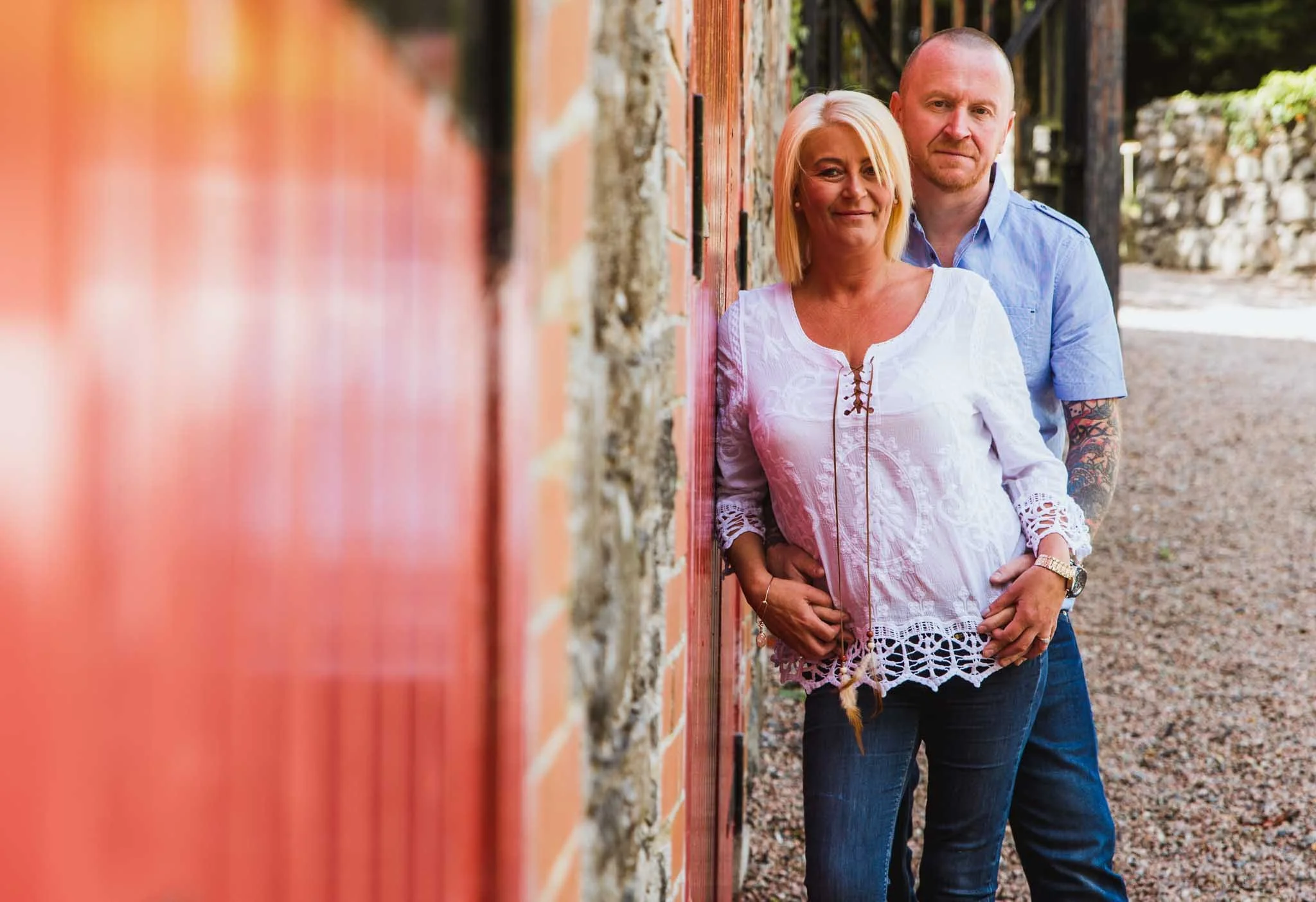  Leaning against the red barn doors with a male behind a female.  