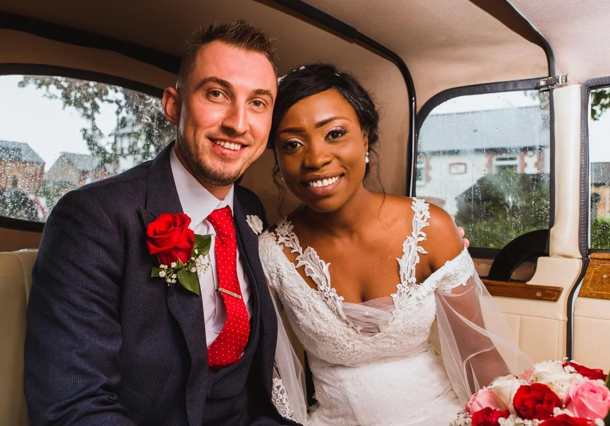 Bride and groom smiling beside each other in a limo.