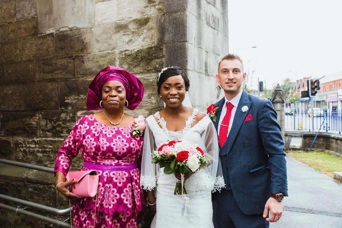 The bride with the groom and mother outside the church.