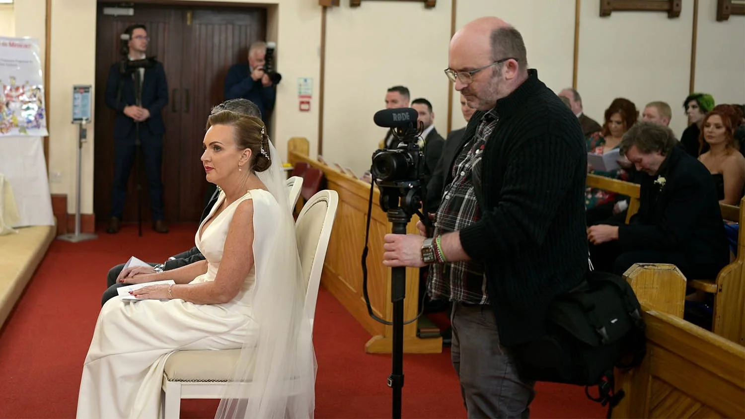 Wedding videographer standing beside the bride and groom during the ceremony in Portadown.
