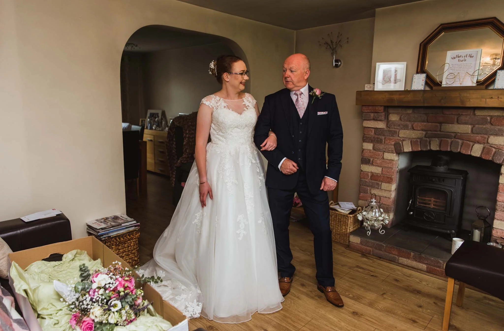 Father looking at daugjter and bride for first look in living room.